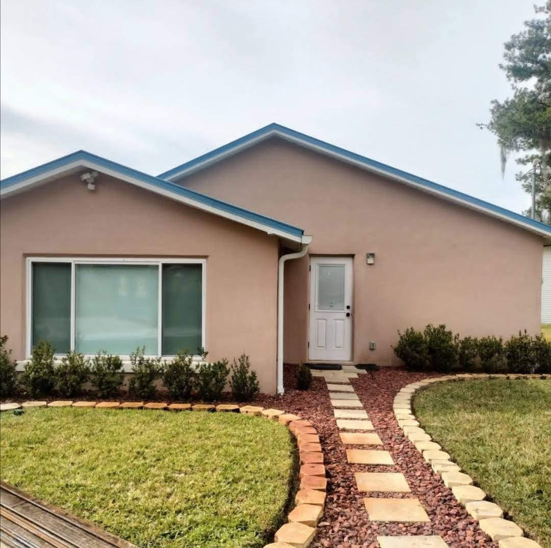 Stucco home in faded pink with blue fascia